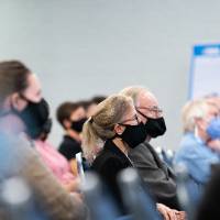 Audience wearing masks listening intently to oral presentation.